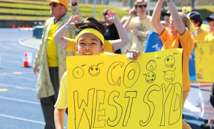 Students hold up posters that say 'go West Syd' on a yellow poster at Sports Carnival 2018